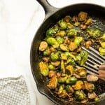 Brussels sprouts with bacon and cream in cast iron skillet on marble counter