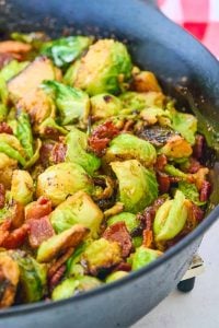 black cast iron skillet filled with browned brussels sprouts with bacon