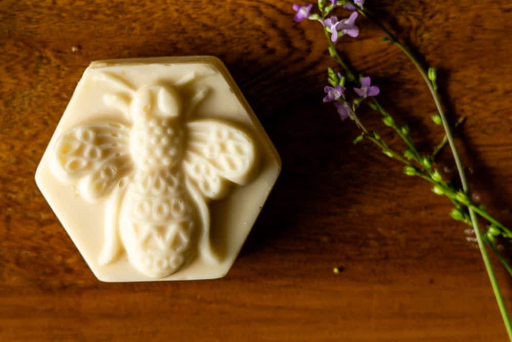 bar of honey and beeswax soap next to flower