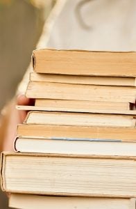 stack of 7 books in woman hand