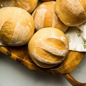 four wheat dinner rolls in bowl, slashed tops and dusted with white flour