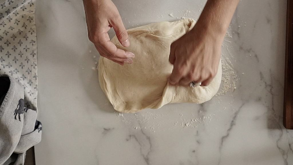 sourdough sandwich dough being rolled up into loaf