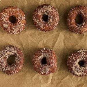 6 doughnuts on parchment covered in cinnamon sugar