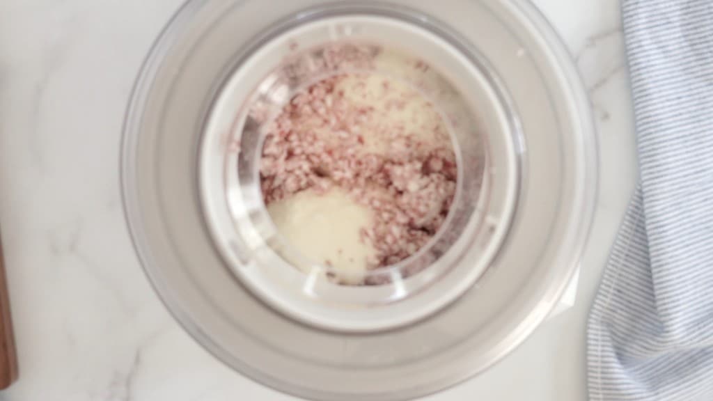 peppermint candies being stirred into vanilla ice cream