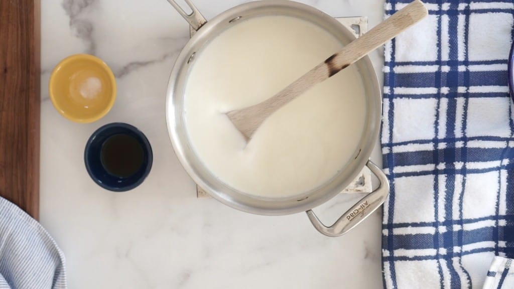 large saucepan on marble counter with milk and heavy cream being heated for homemade candy cane ice cream