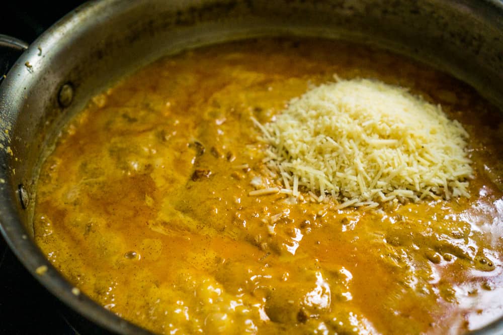 shredded parmesan being added to smoky pasta sauce