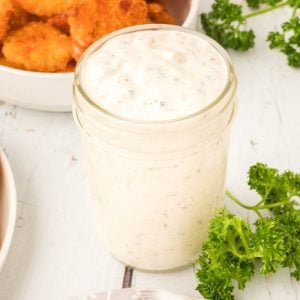 small mason jar of homemade tartar sauce with fried shrimp in background