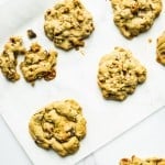 7 large chocolate chip cookies with caramel and pretzel on parchment paper