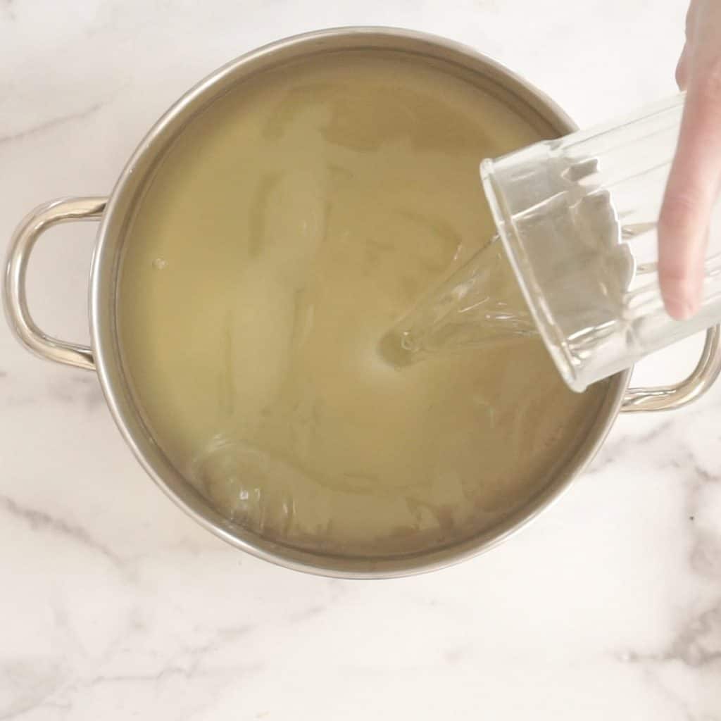 lye water glass being poured into pot of. melted oils