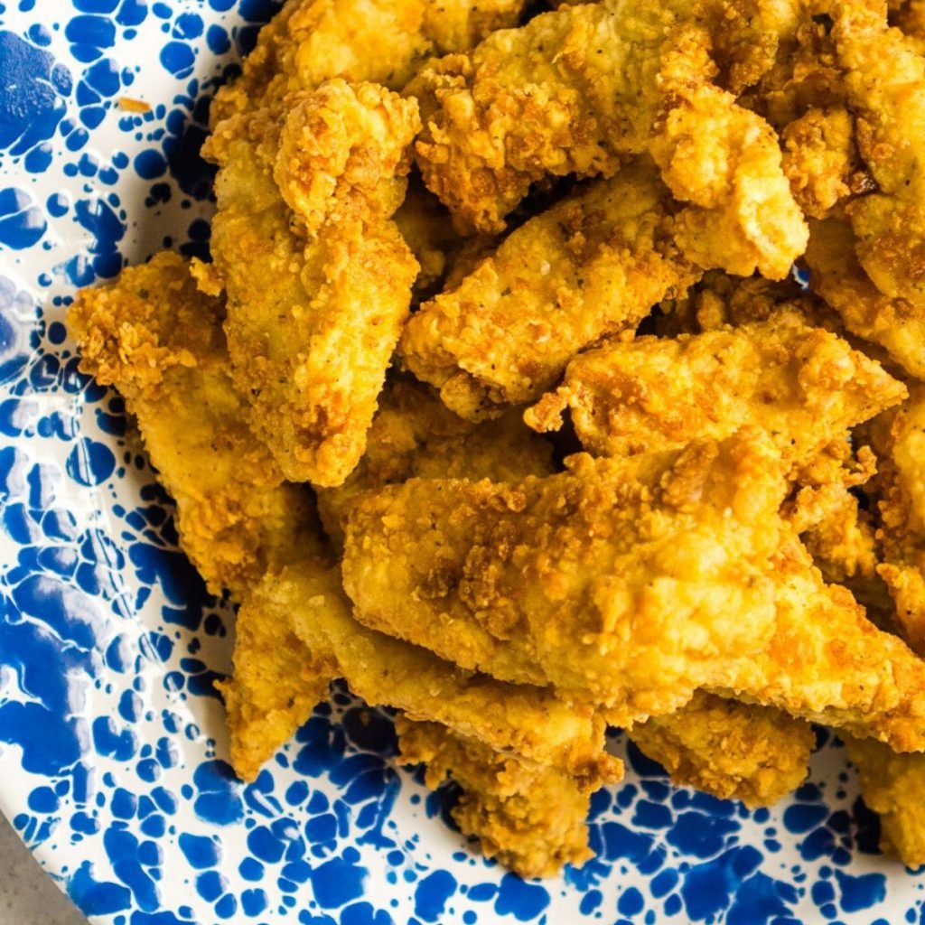 assiette bleue et blanche avec des tendres de poulet frits