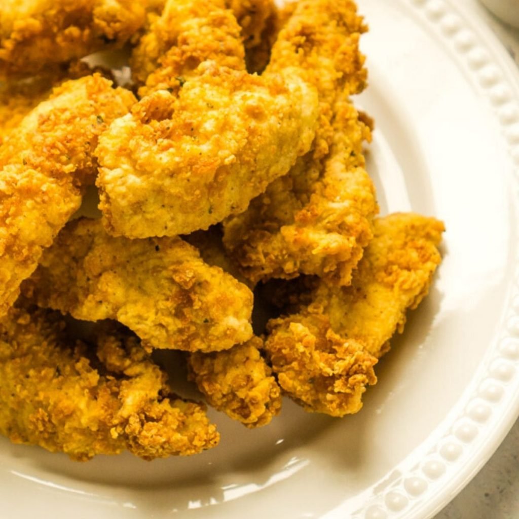 off white plate piled with fried chicken tenders