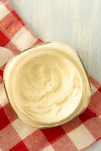 jar of homemade body cream on red and white checked cloth