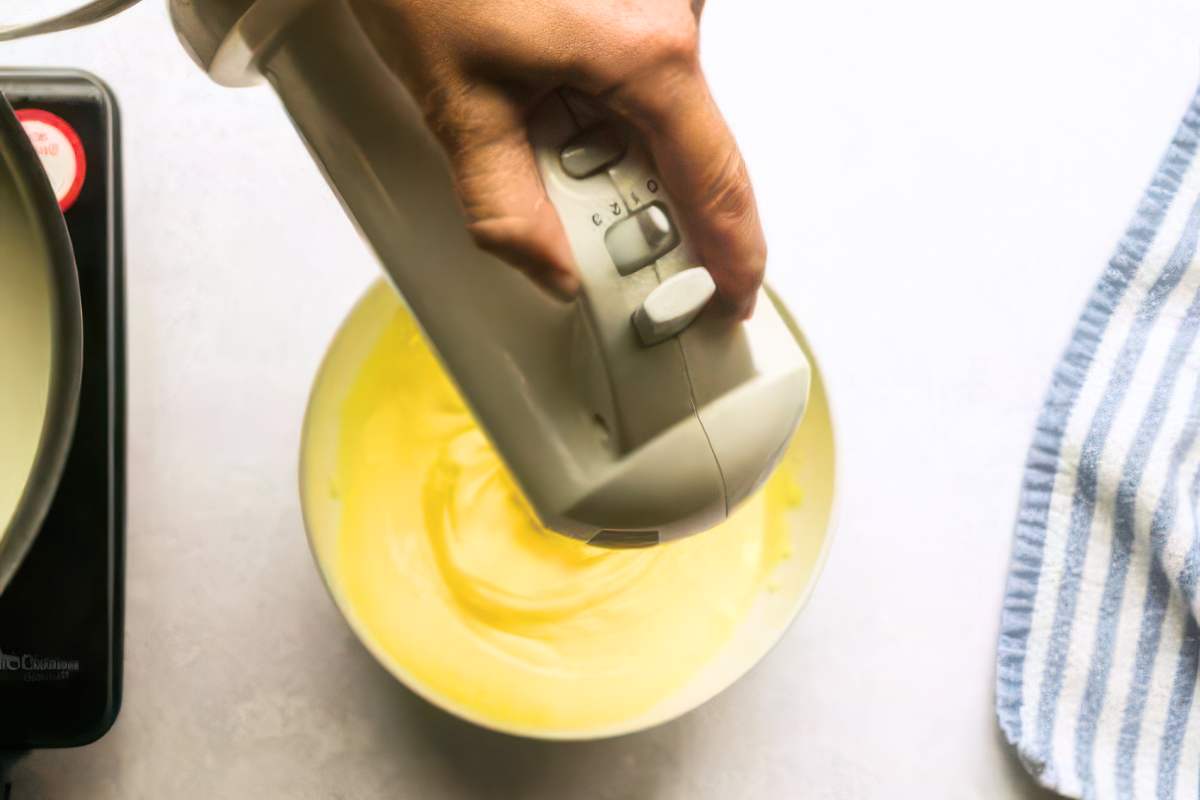 Hand using an electric hand mixer to beat egg mixture .