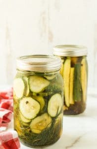 2 mason jar quart jars of dill pickles on white surface