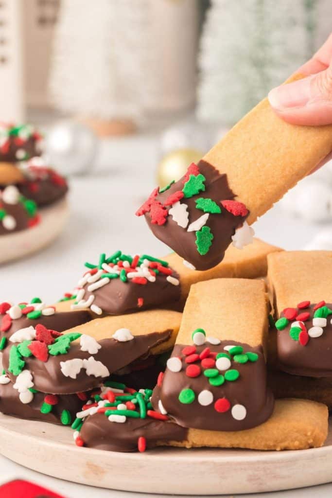 plate of christmas shortbread with someone picking up one