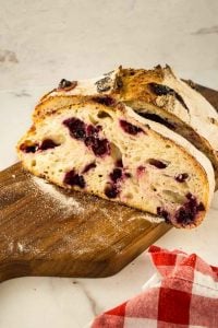 loaf of sourdough bread with blueberries and lemon on cutting board