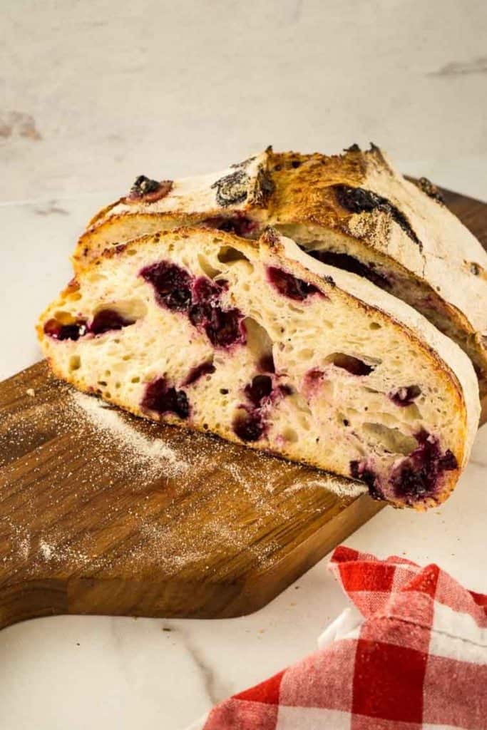 loaf of sourdough bread with blueberries and lemon on cutting board