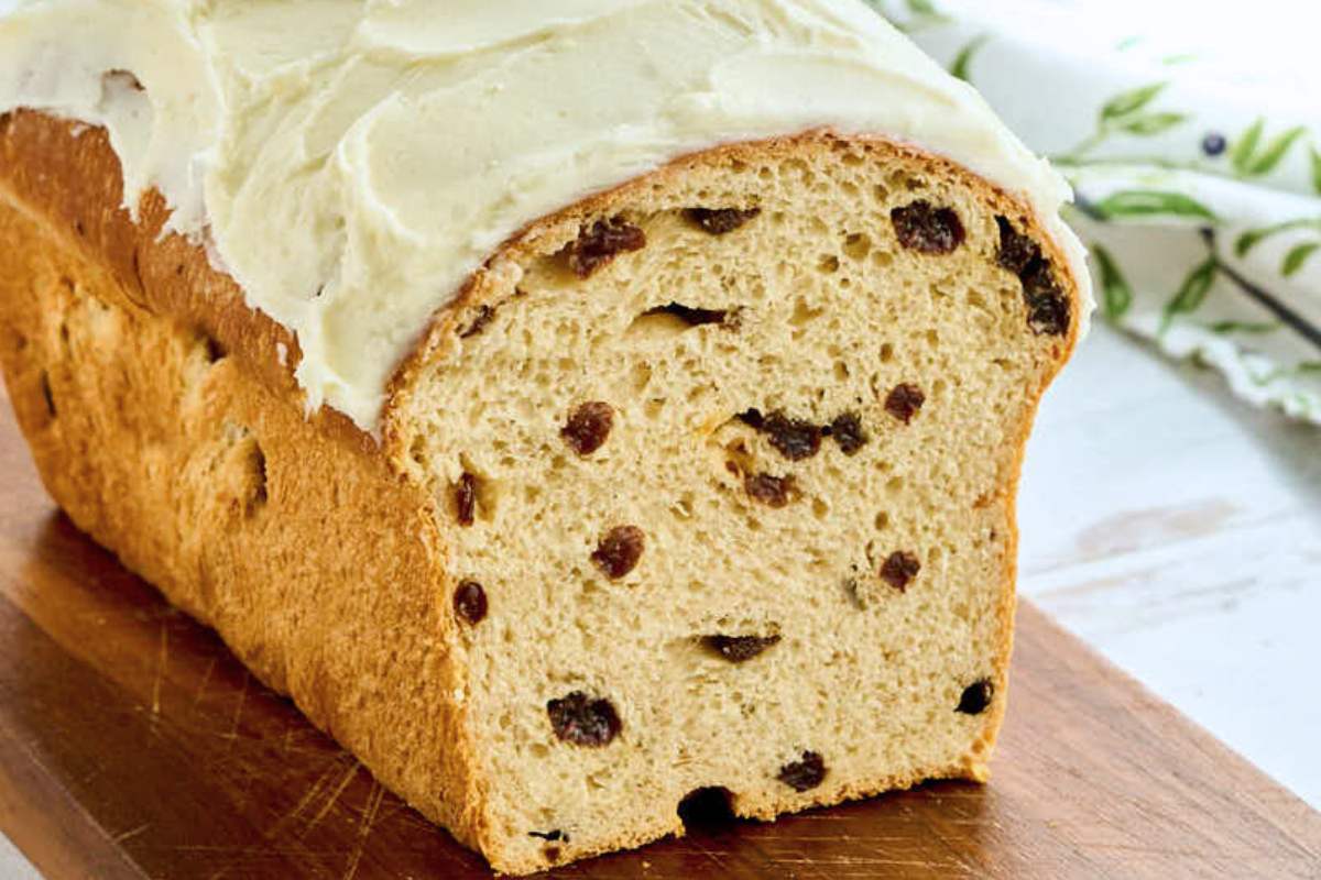 side view of cut bread loaf with icing on top showing raisins inside.
