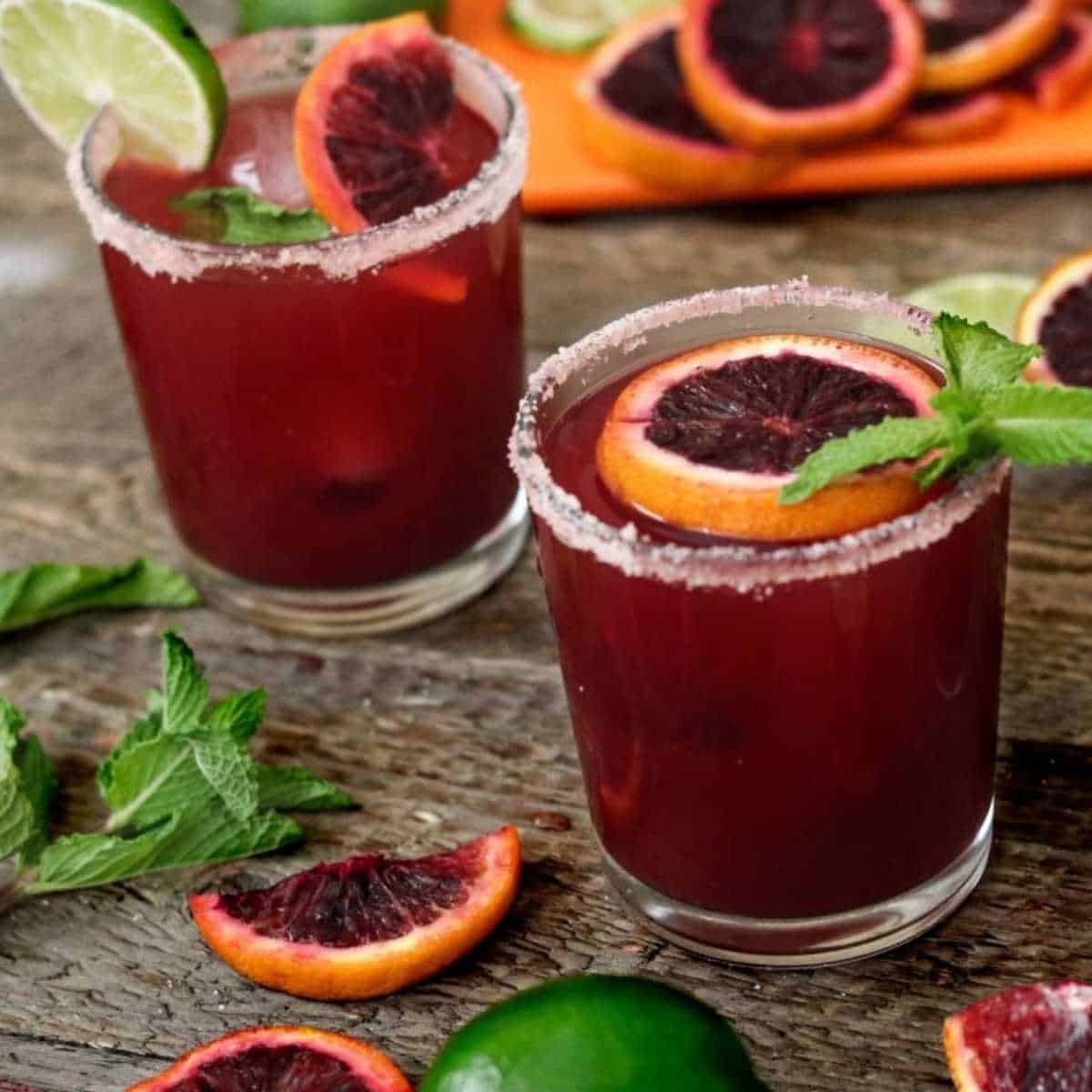 2 blood orange margarita glasses on wood surface