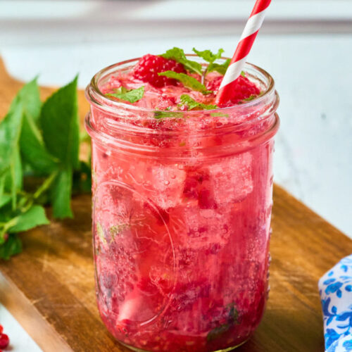 finished raspberry mojito with straw in front of window.