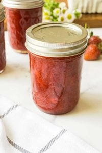 half pint jar of strawberry jam on white counter