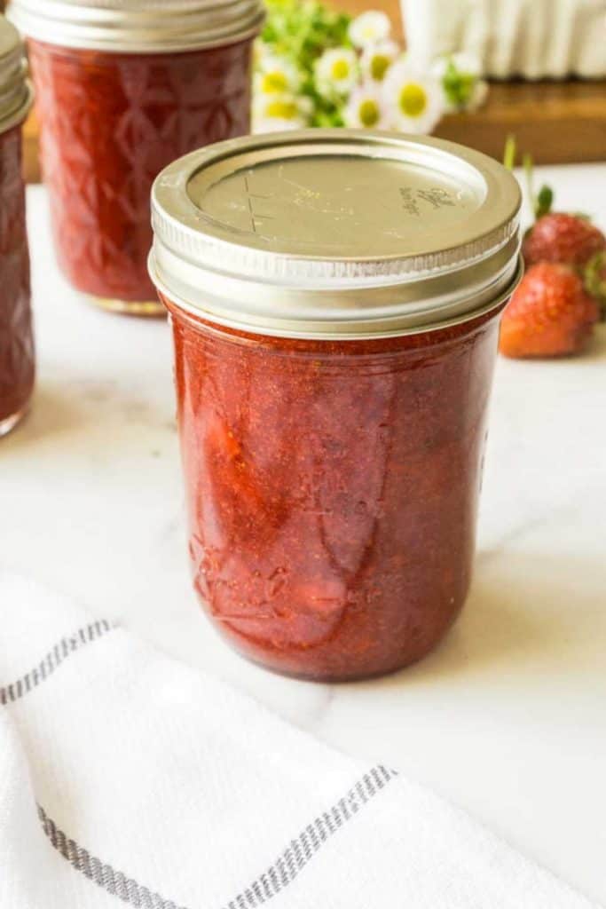 half pint jar of strawberry jam on white counter