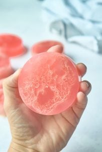 pink, round loofah soap in hand