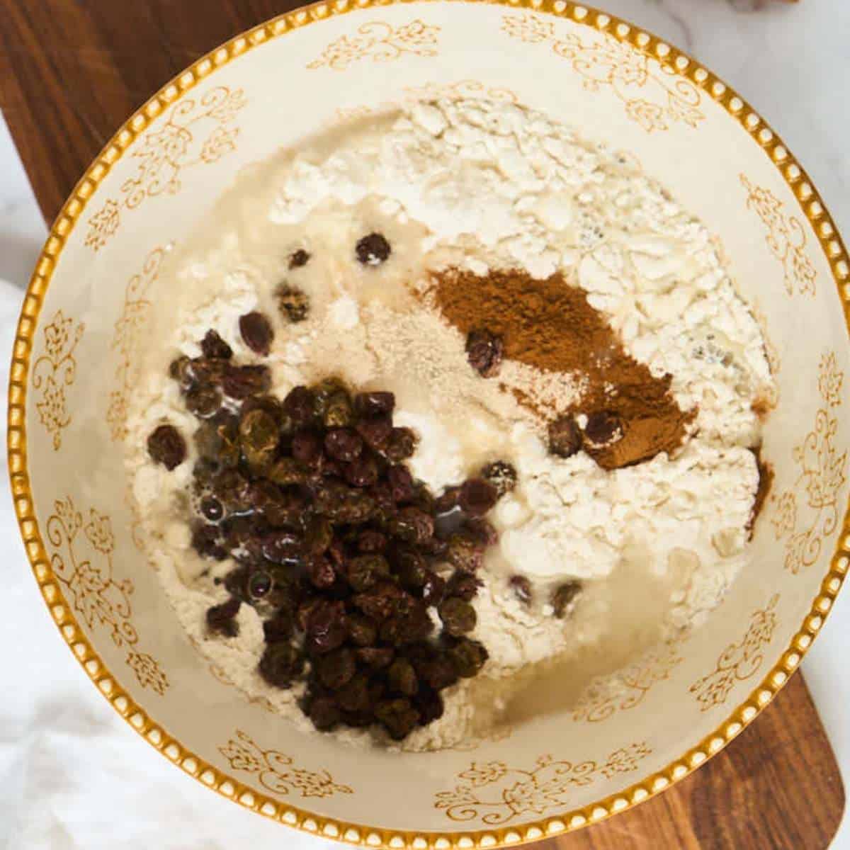 large mixing bowl with flour, water, cinnamon, and raisins