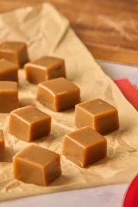 caramel pieces sitting on parchment paper on counter.