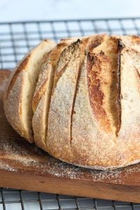 loaf of sourdough bread on cooling rack being sliced