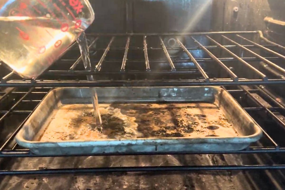Water being poured into a hot pan in the oven.