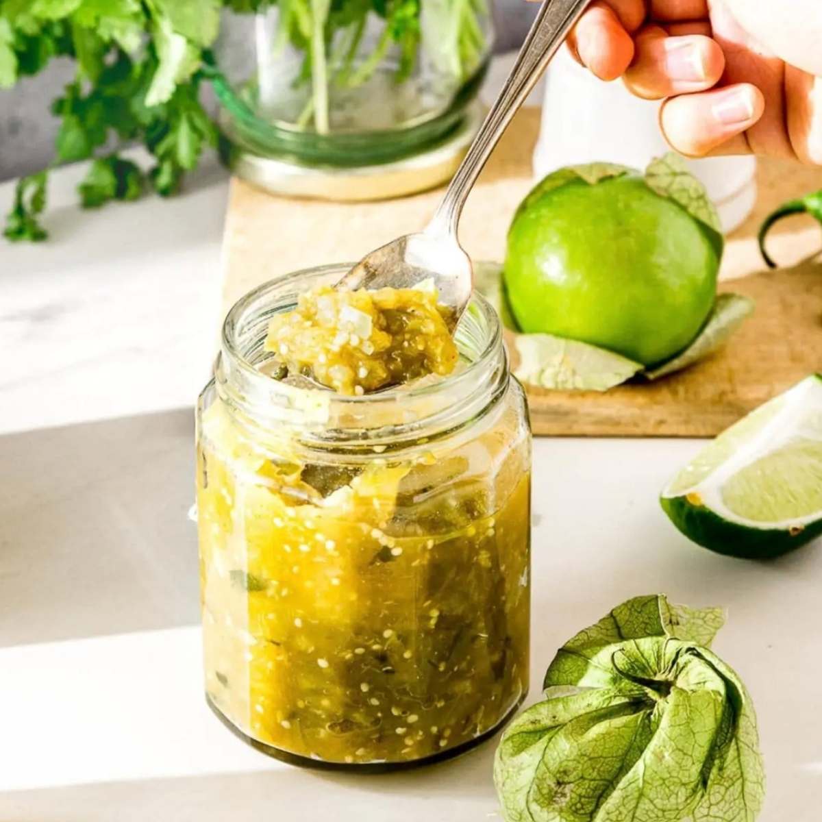 jar with green salsa and limes in background
