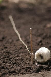 garden soil with ball of twine and stick in ground
