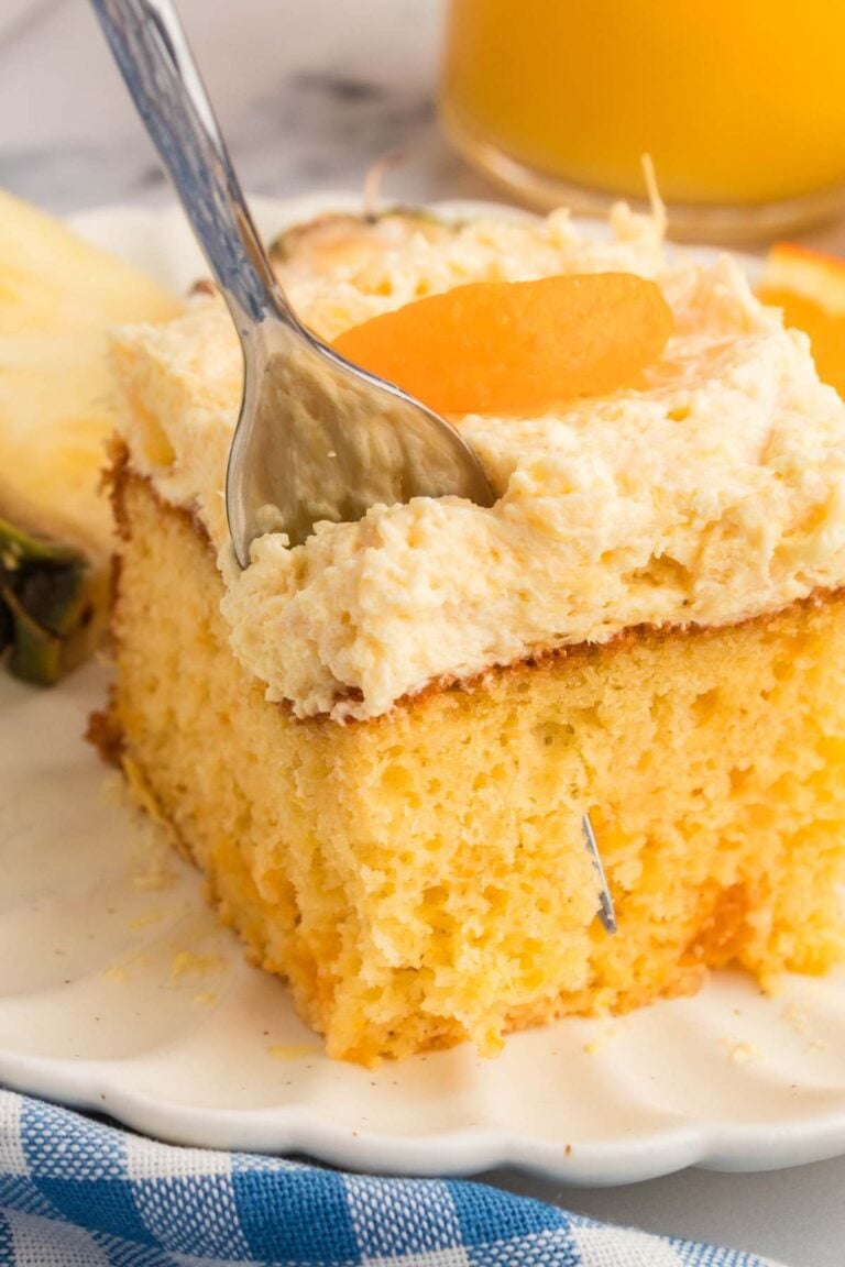 Plated square cake with orange slice on top.