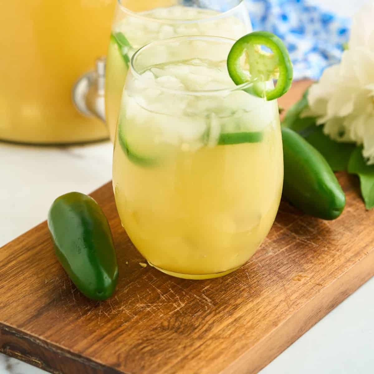 glass of sangria with jalapeno slices on wooden board with jalapenos.