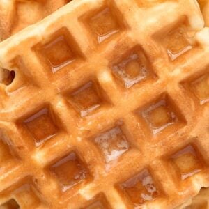 close up view of waffles with butter and syrup.