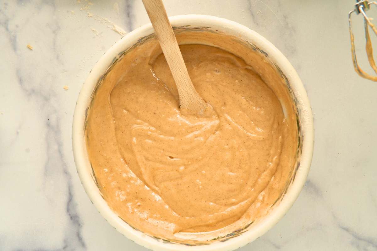 Smooth cake batter in a mixing bowl with a wooden spoon resting inside