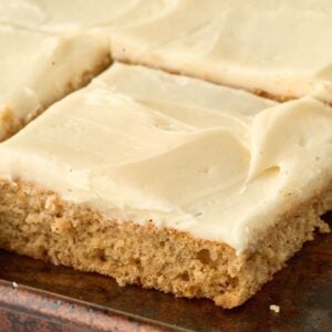 square piece of cake with cream cheese frosting in jelly roll pan.