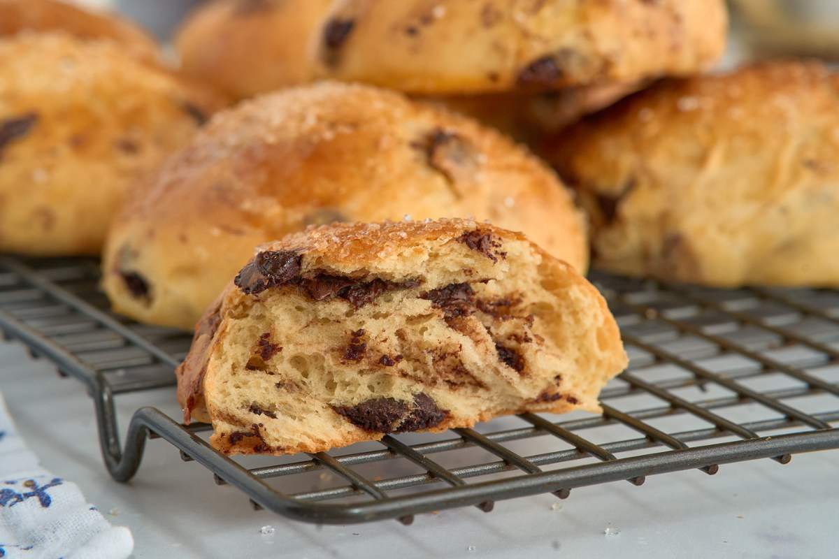 Baked chocolate chip brioche roll cut open on cooling rack.