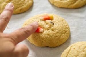 hand pressing candy corn onto baked cookie