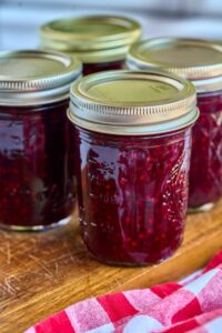 4 jars of finished jam on wooden counter
