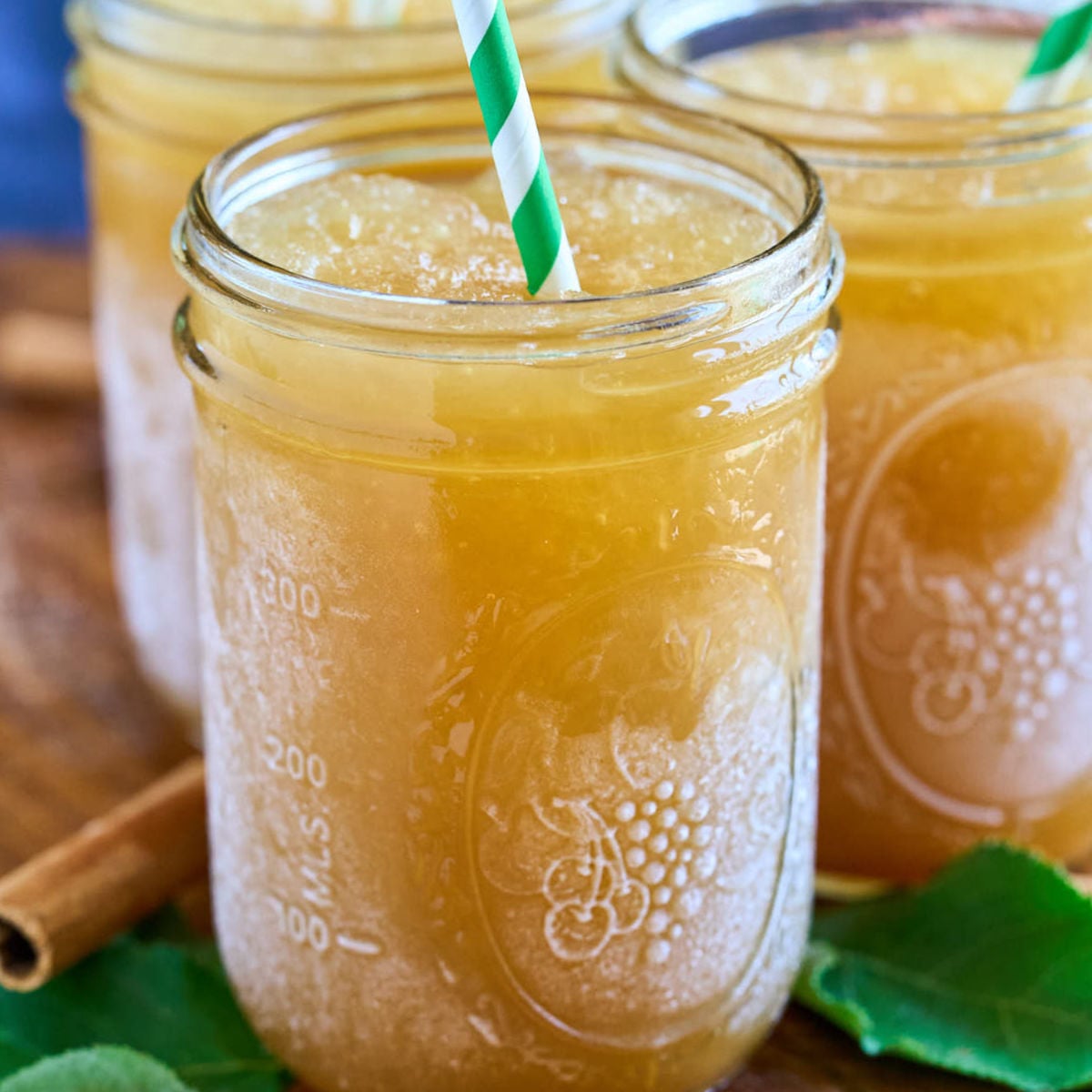 mason jar of frozen apple cider with green and white straw.