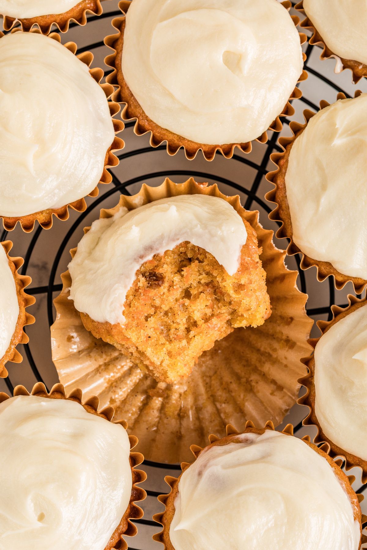 Overhead view of frosted carrot cupcakes with one bitten open.