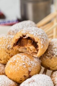 pile of deep fried snickers on plate with bite missing from one.