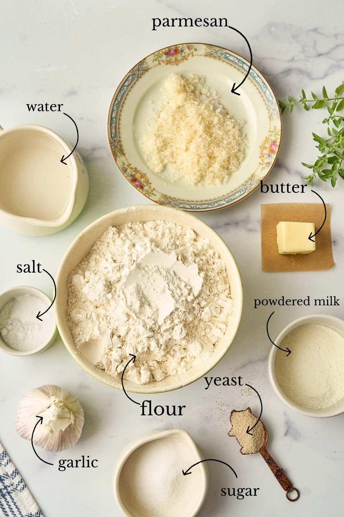 Ingredients for dinner rolls laid out in bowls including flour, water, and parmesan.