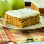 large square slice of pumpkin cake with apple in background.
