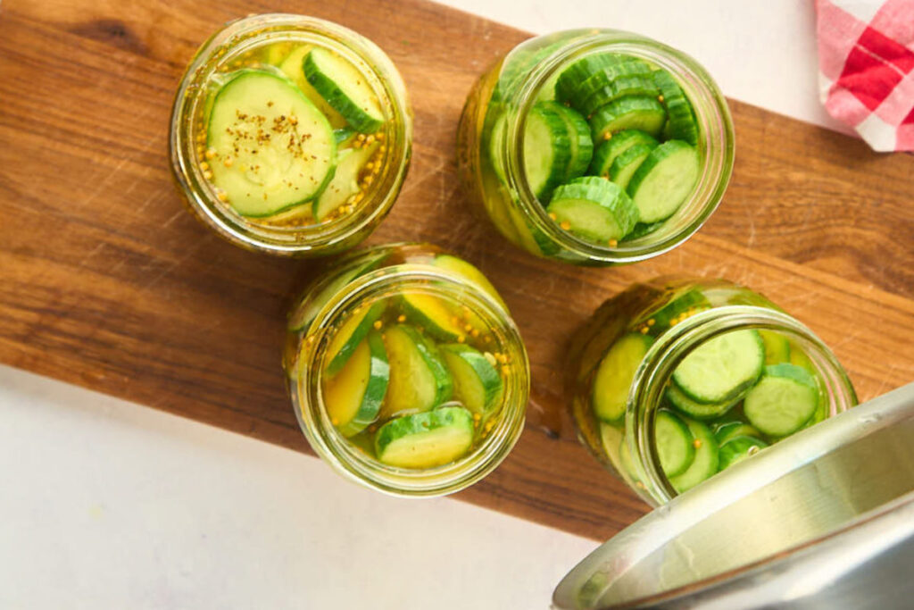 saucepan pouring brine into cucumbers.