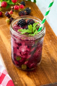 blackberry mojito in mason jar on wooden board.