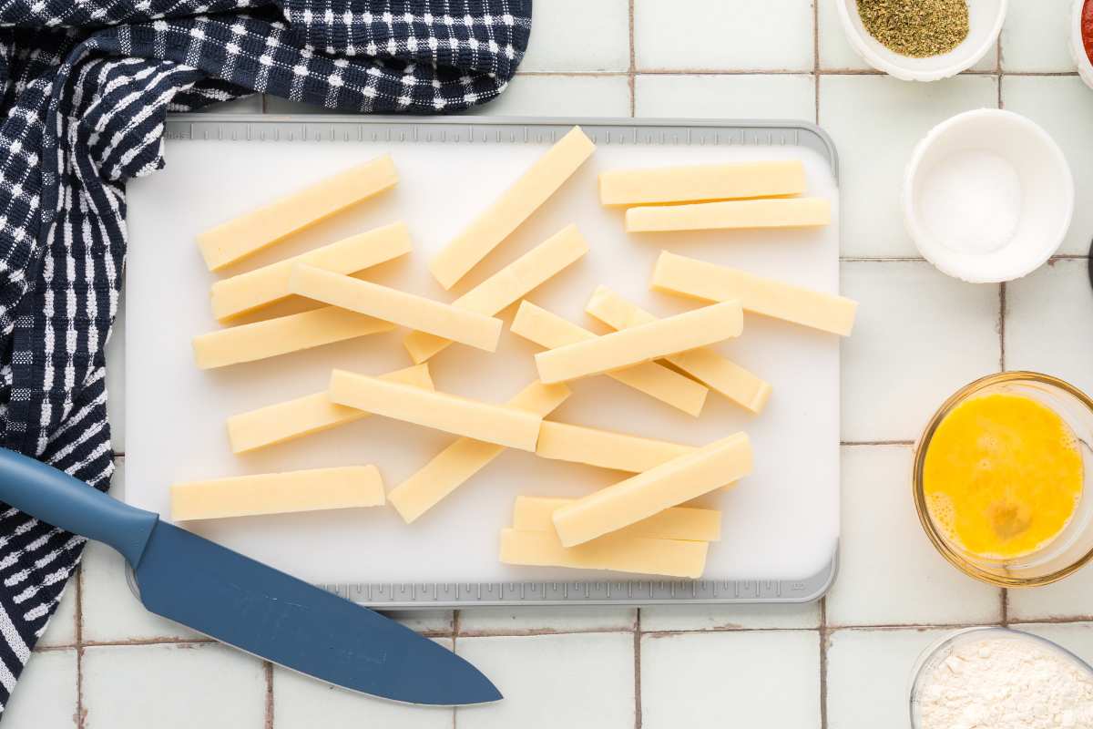 mozzarella sticks cut up on tray with knife nearby.