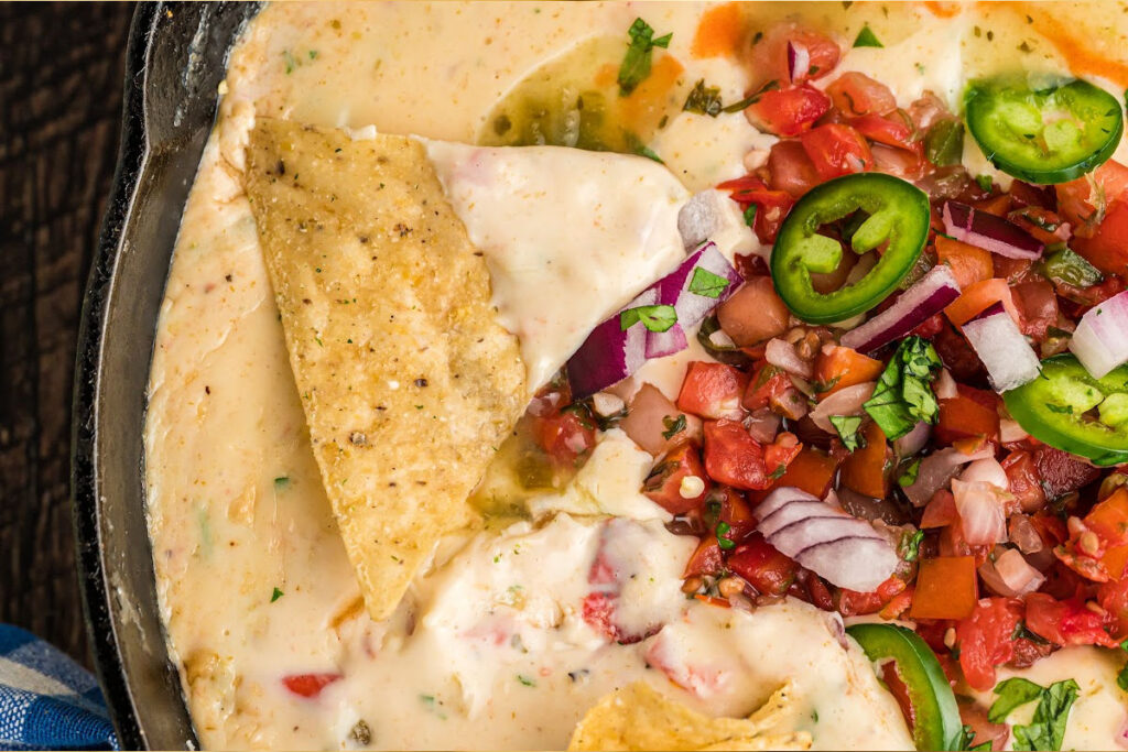 chip being dipped into queso.